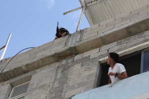 A Palestinian looks out of his window to find armed Israeli soldiers using the roof of his home in Al Arrub refugee camp near Hebron